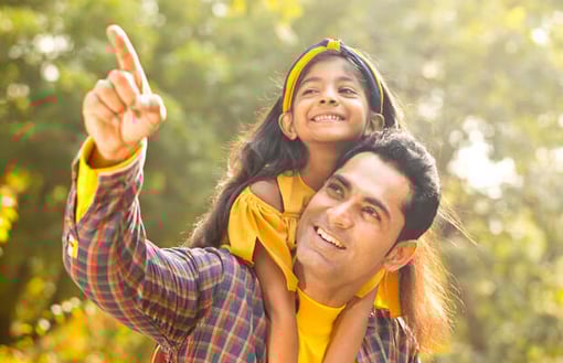 Vonage India Image of man walking outside carrying daughter on his back