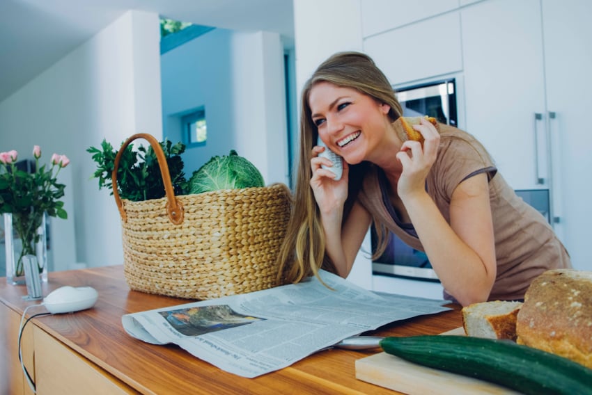 Woman with home VoIP phone Woman with VoIP home phone to her ear leaning on kitchen counter