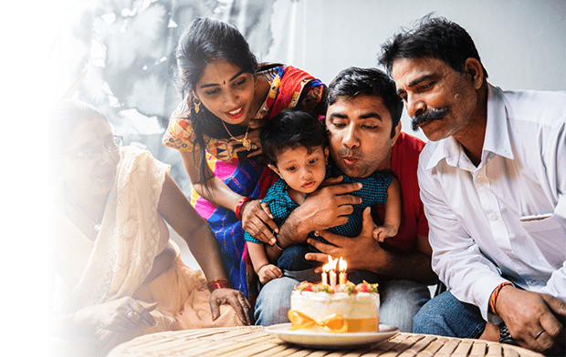 Image of a family blowing out birthday cake candles together.